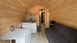 Un intérieur compact en bois, comprenant un coin cuisine, un canapé et un espace douche.
