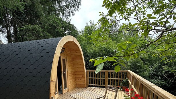 Une terrasse en bois avec une table et des chaises, une arche en bois et des plantes en pot.