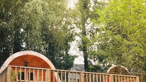 Une terrasse en bois dotée de deux structures semi-circulaires en bois, probablement destinées à servir de coin salon ou de salle à manger, soutenues par une ossature en bois renforcée par des traverses.