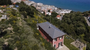 A coastal town with a prominent red building surrounded by greenery and a view of the sea.