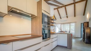 A modern kitchen with wooden beams, white cabinetry, and a large island.
