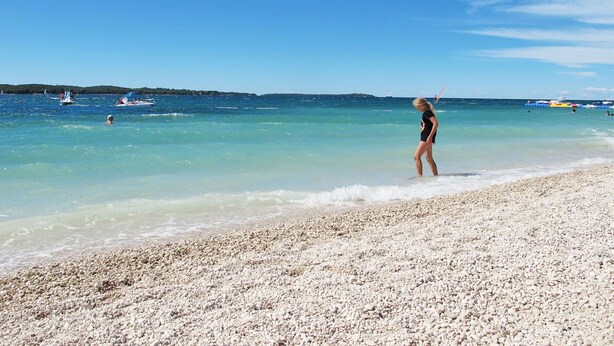 A beach with clear water and a pebbly shore.