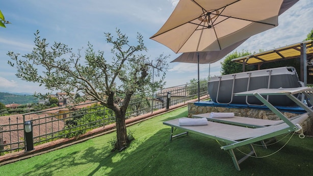 A terrace with a table and chairs, a large umbrella, and a view of the surrounding landscape.