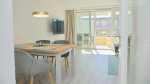 A modern dining area with a wooden table, grey chairs, and a flat-screen TV mounted on the wall.