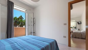 A bedroom with a bed, a sliding glass door to a balcony, and a view of palm trees. - 4128 Villino Giovanna by Barbarhouse (Melendugno)