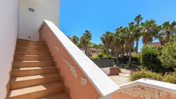 A staircase leading to a balcony with a stone wall, palm trees, and a clear blue sky. - 4128 Villino Giovanna by Barbarhouse (Melendugno)