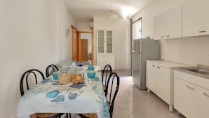 A kitchen with white cabinets, a refrigerator, and a dining table with chairs. - 4128 Villino Giovanna by Barbarhouse (Melendugno)