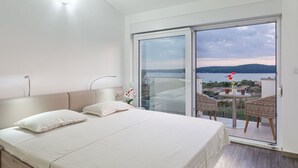 A bedroom with a large bed, a sliding glass door leading to a balcony with a table and chairs, and a view of a body of water. - Wonderful private villa for 8 guests with A/C, private pool, WIFI, TV, terrace and pets allowed (Medulin)