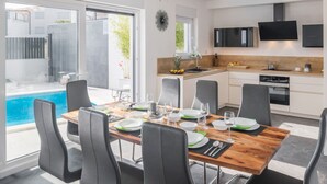 A modern kitchen with a dining area, a pool view, and a TV mounted above the counter. - Wonderful private villa for 8 guests with A/C, private pool, WIFI, TV, terrace and pets allowed (Medulin)