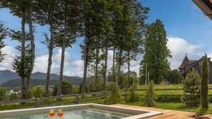 Une terrasse en bois avec un jacuzzi, des chaises longues et une vue sur un paysage montagneux.
