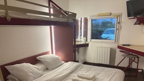 A bunk bed room with a desk, a chair, and a window with a view of the outside.