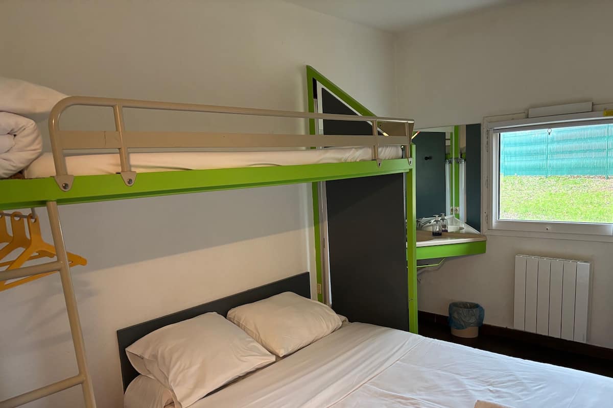 A bunk bed room with a window, a small sink, and a radiator.