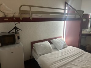 A bunk bed with a headboard, a microwave, and a small refrigerator in a hotel room. - HOTEL PARIS VALENCE (Bourg-de-Peage)