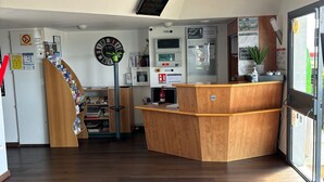 A hotel reception area with a wooden reception desk, a digital clock, and a fire alarm.
