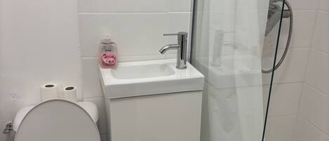 A bathroom with a toilet, sink, and shower.