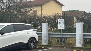 A white car parked near a gated area with a building in the background.