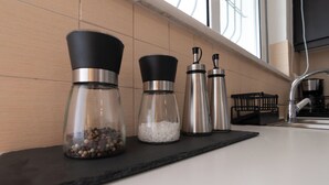 A kitchen counter with three stainless steel containers, one with black lids and two with silver lids, containing different spices and grains.