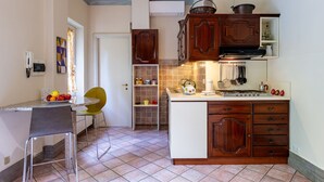 A kitchen with wooden cabinets, a sink, and a stove. There is a chair and a small table with fruit on it. - Beautiful private villa for 6 guests with A/C, TV, terrace and pets allowed (Invorio)