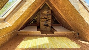 Un dormitorio abuhardillado con paredes de madera, una chimenea de ladrillo y tragaluces.