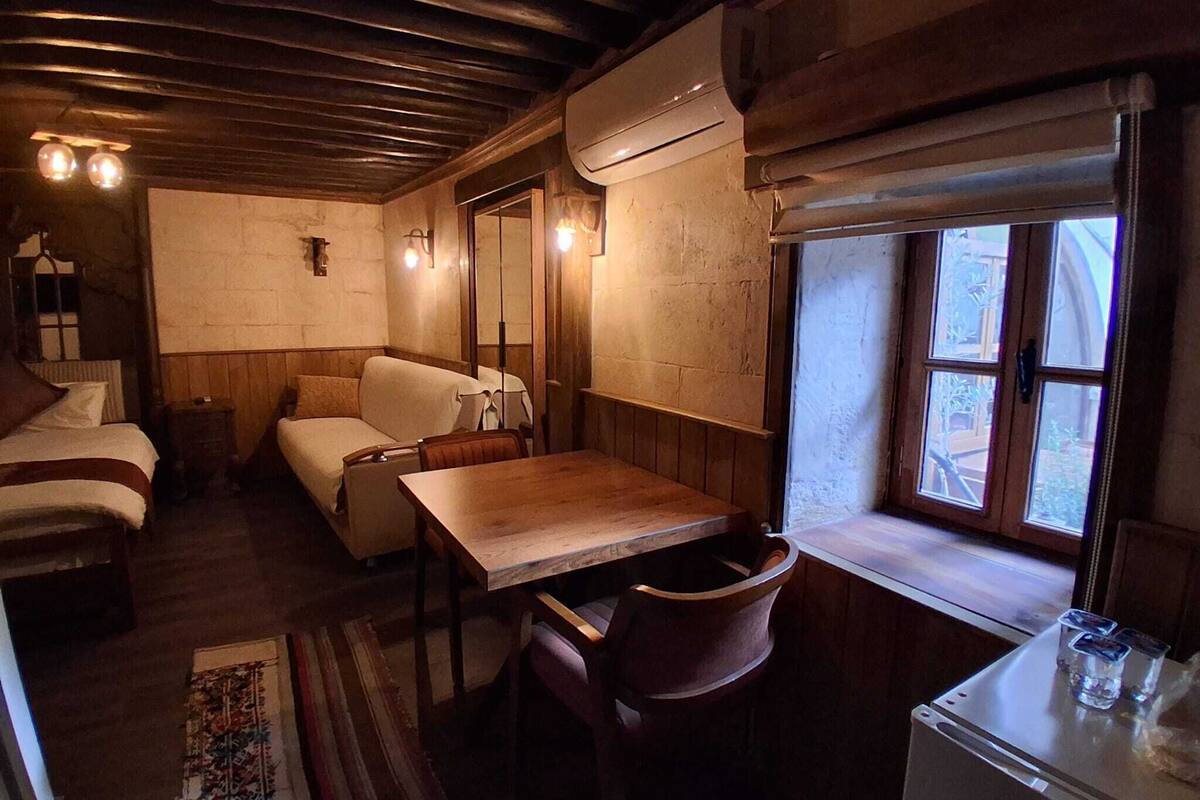 Um quarto acolhedor estilo cabana, com teto de madeira, uma cama, um sofá, uma mesa de jantar e um frigorífico.