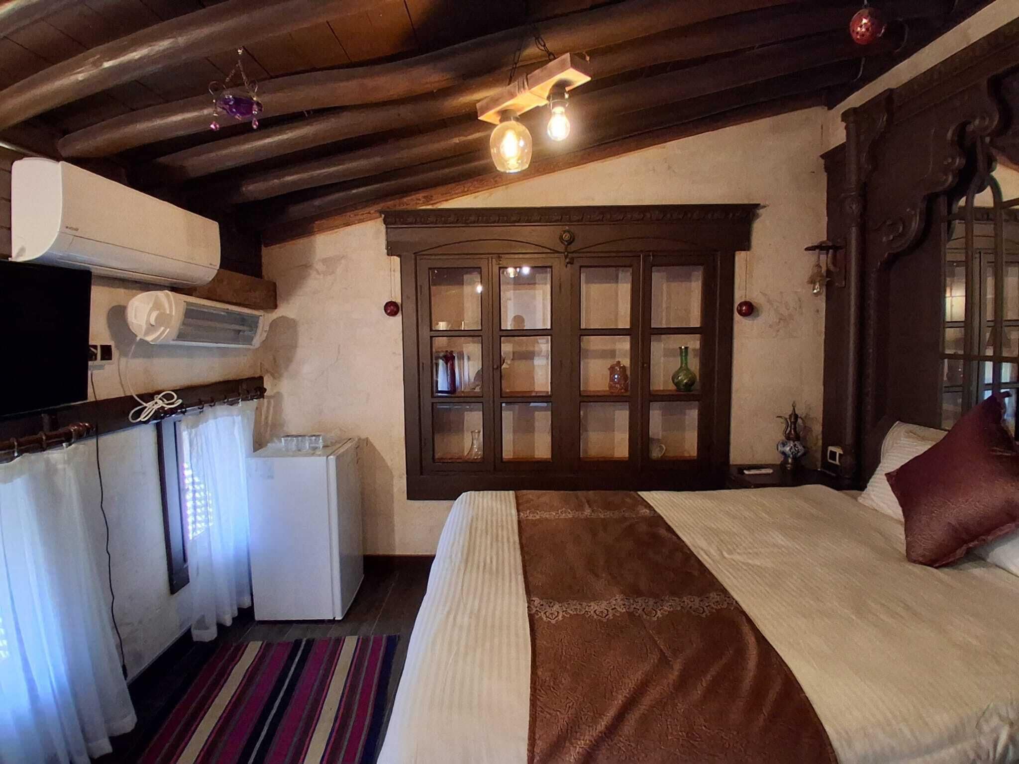 A cozy room with a bed, a window with a view, a radiator, and a television.