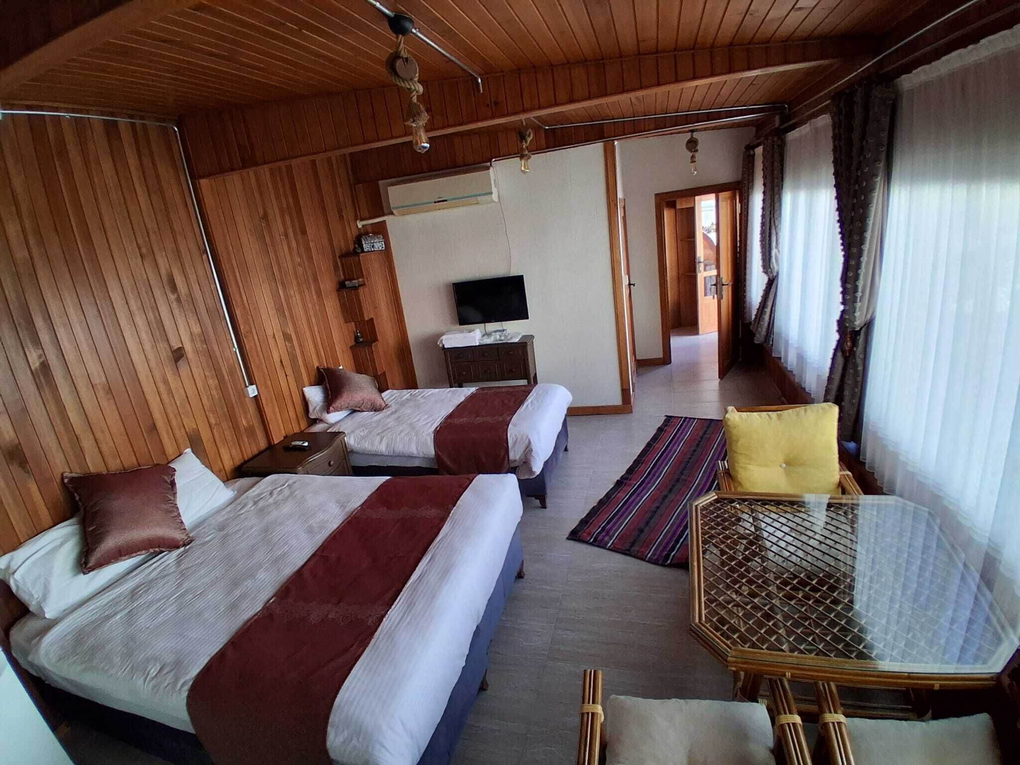 Una habitación con dos camas, televisión, una mesita y una ventana con cortinas.