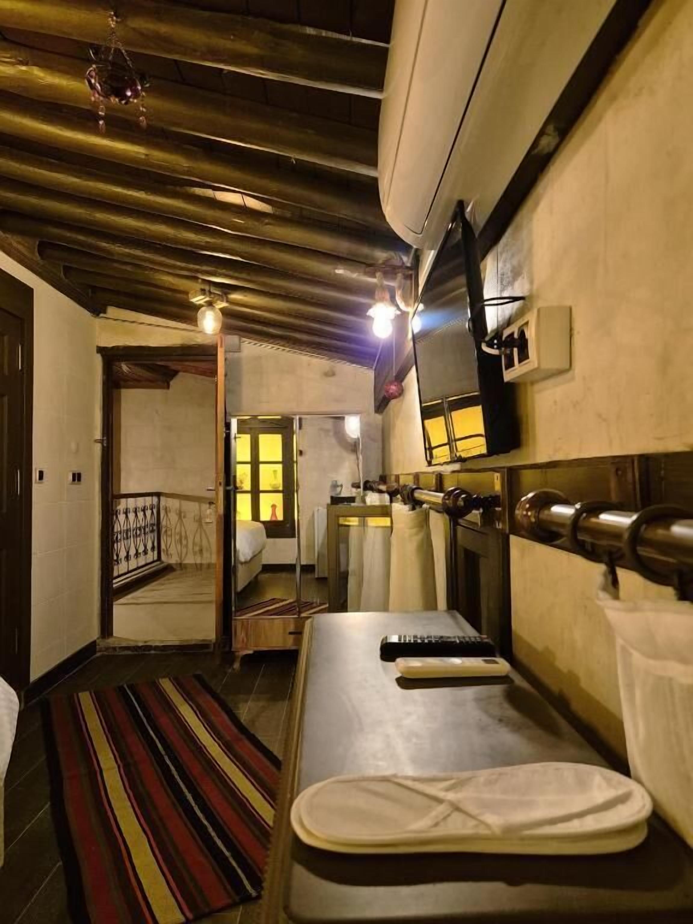 A room with a bed, a TV mounted on the wall, and a window with curtains.