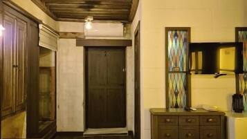 A room with two beds, a wooden ceiling, a small table, and a mirror.
