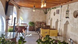 Un intérieur chaleureux avec des poutres en bois, un coin repas et un espace détente avec des coussins.