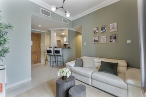 A living room with a sofa, a coffee table, and a kitchen area in the background.