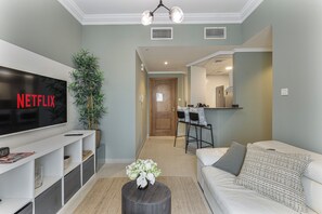 A living room with a flat-screen TV, a sofa, a coffee table, and a plant.