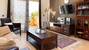 A living room with a sofa, a wooden coffee table, a TV, a clock, and a cabinet with glass doors.