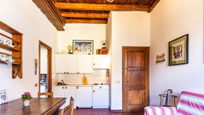 A compact kitchen with white cabinets, a wooden dining table, and a striped sofa. - Cosy apartment for 3 guests with WIFI and patio (Gravedona)
