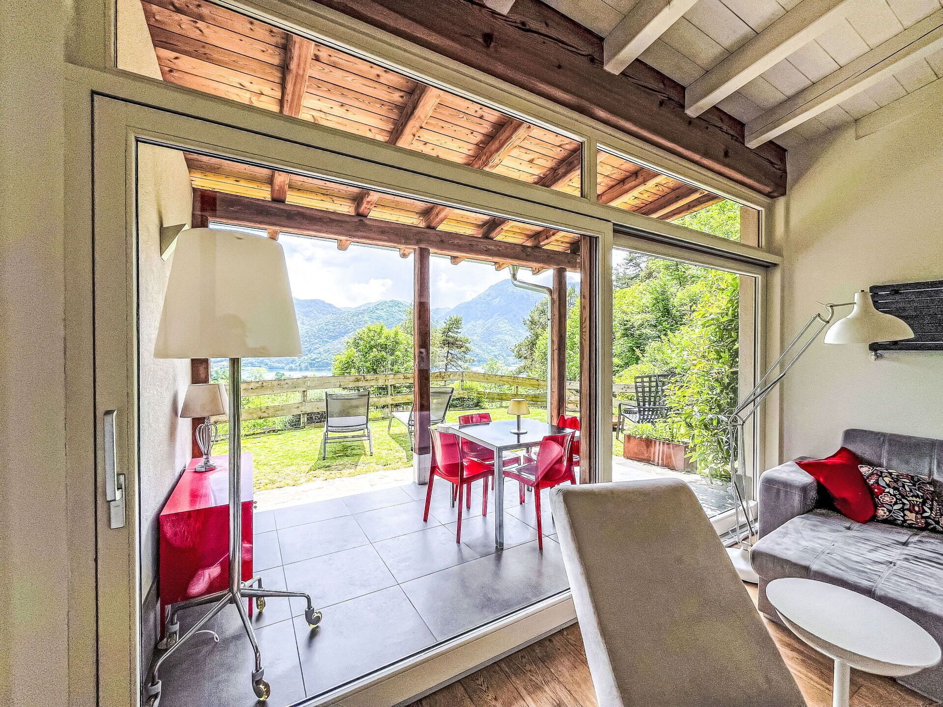 Quarto com porta de vidro deslizante que dá para um pátio ao ar livre com mesa, cadeiras, sofá e luminária.