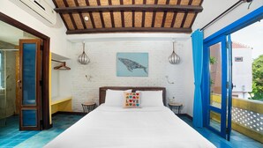 A bedroom with a large bed, a blue door, a white brick wall, and a blue and white tiled floor. - Loft House 2BR Seaside An Bang Beach (Da Nang)