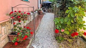 A narrow gravel path leading to a building with a stone wall and a metal gate.