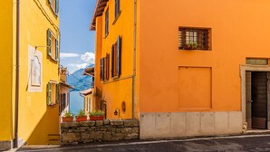 Eine enge Straße mit gelb-orangen Gebäuden, Steinstufen und einem Berg im Hintergrund.