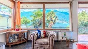 A cozy room with a large window overlooking a scenic coastal view, a plush sofa, and a small table with a plant.