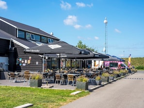 Outdoor seating with umbrellas, a building with a dark facade, and a clear sky.