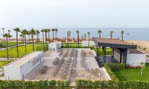 A rooftop dining area with multiple tables and chairs, surrounded by palm trees and a view of the sea. - Lusso Sorgun (Manavgat)