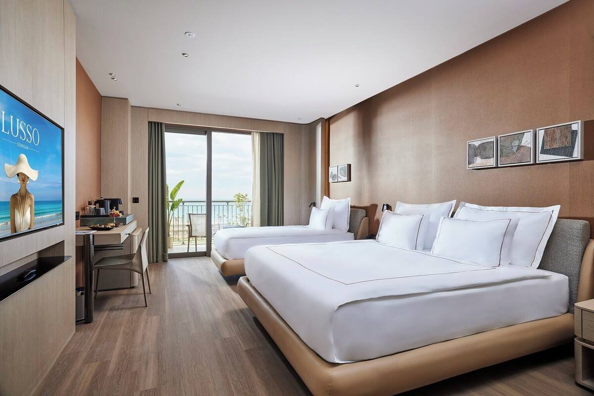 A hotel room with two beds, a desk, and a TV.