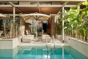 A pool area with lounge chairs, a sun umbrella, and a view of a building with large windows. - Lusso Sorgun (Manavgat)