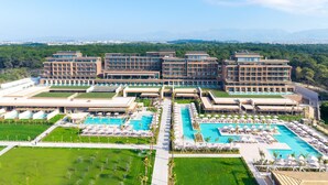 Een modern hotel met meerdere gebouwen, een groot centraal zwembad en omliggende groene ruimtes.