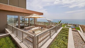 Een modern balkon buiten met een hottub, zitplaatsen en uitzicht op de oceaan.