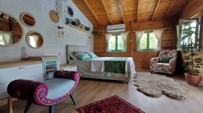 Cozy room with a comfortable bed, floral armchair, and potted plant.