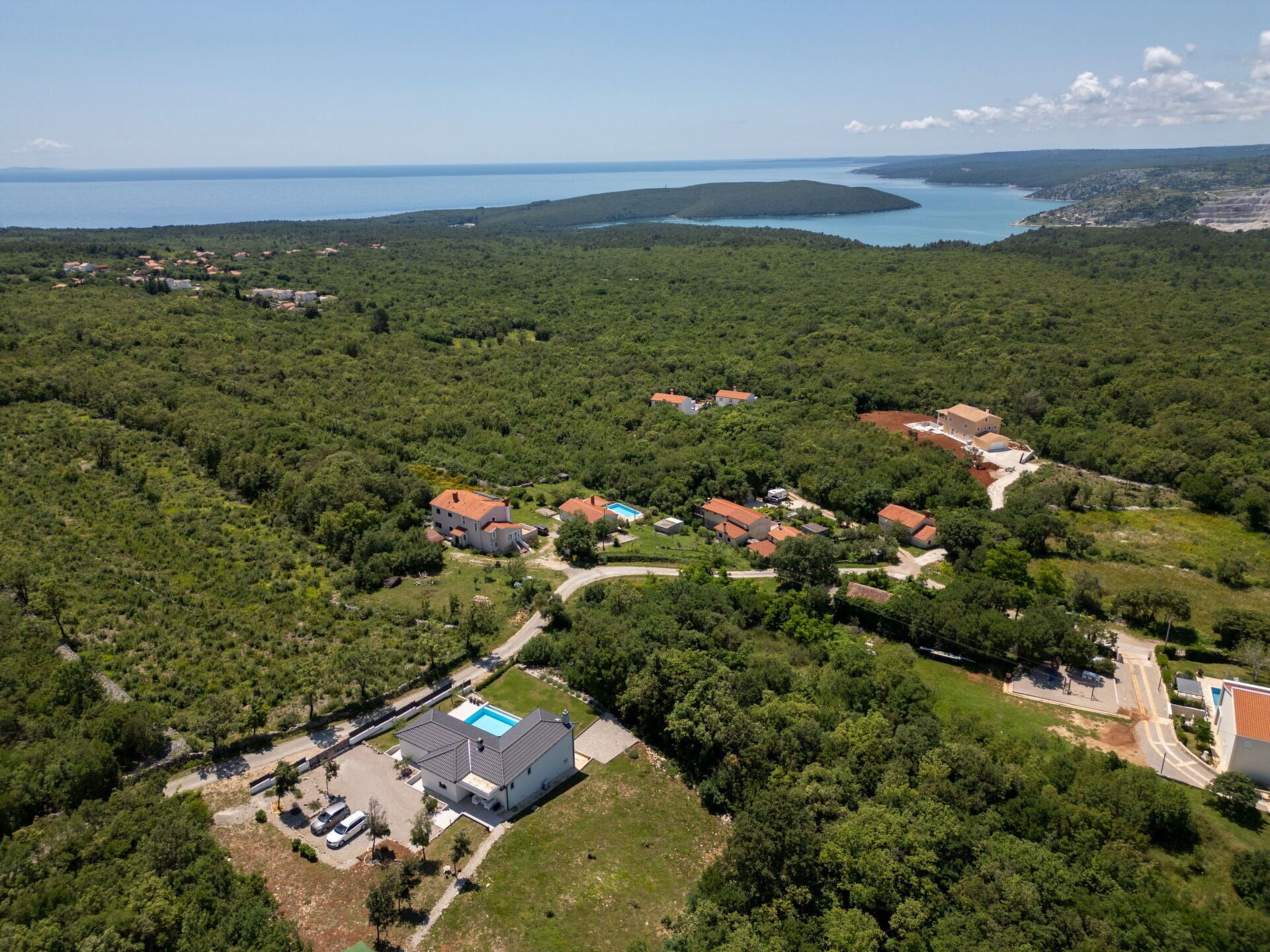 Vue aérienne d’un quartier résidentiel avec des maisons, une piscine et une route.