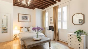 Ein Schlafzimmer mit Bett, Nachttisch, Kommode und einer Kronleuchter.
