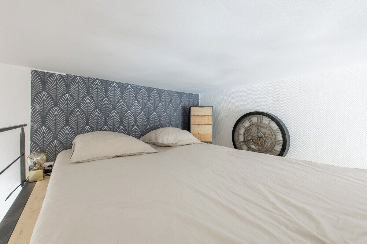 A bedroom with a bed, a clock, and a patterned headboard.