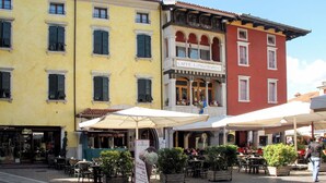 Una strada con tavoli all'aperto, un chiosco di gelato e un edificio con un cartello che riporta la scritta 'CAFFE' LONGOBARDO'.