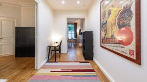 A hallway with a striped rug, a dining area with a table and chairs, and a poster on the wall. - Central 1BR Quai de Seine in the Marais district (Paris)